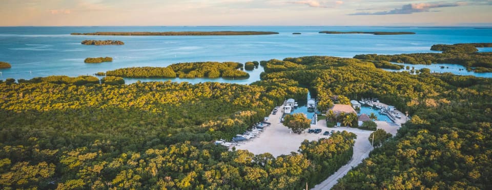 Aerial sunset view of Angler House Marina nestled among mangroves and calm turquoise water in the Florida Keys, with boats docked at the resort