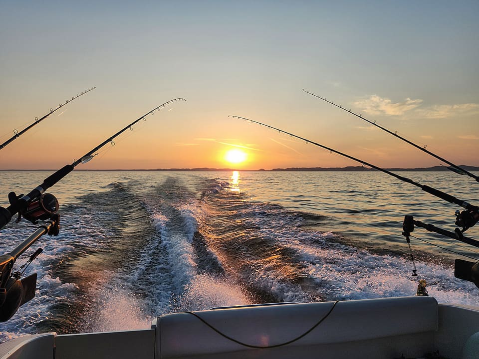 Group of friends enjoying a relaxing charter boat ride on the ocean. The sky is clear, and the waves are calm