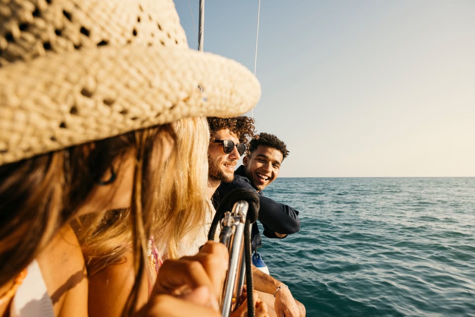Group of friends enjoying a relaxing charter boat ride on the ocean. The sky is clear, and the waves are calm